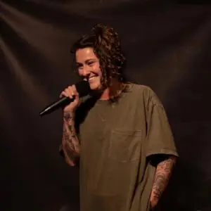 Kyla Cobbler in a green shirt onstage with a microphone